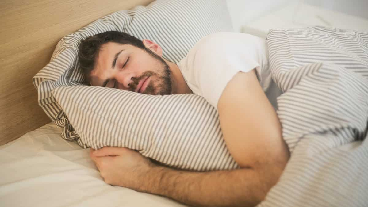 homem dormindo sonhando em uma cama agarrado com travesseiro